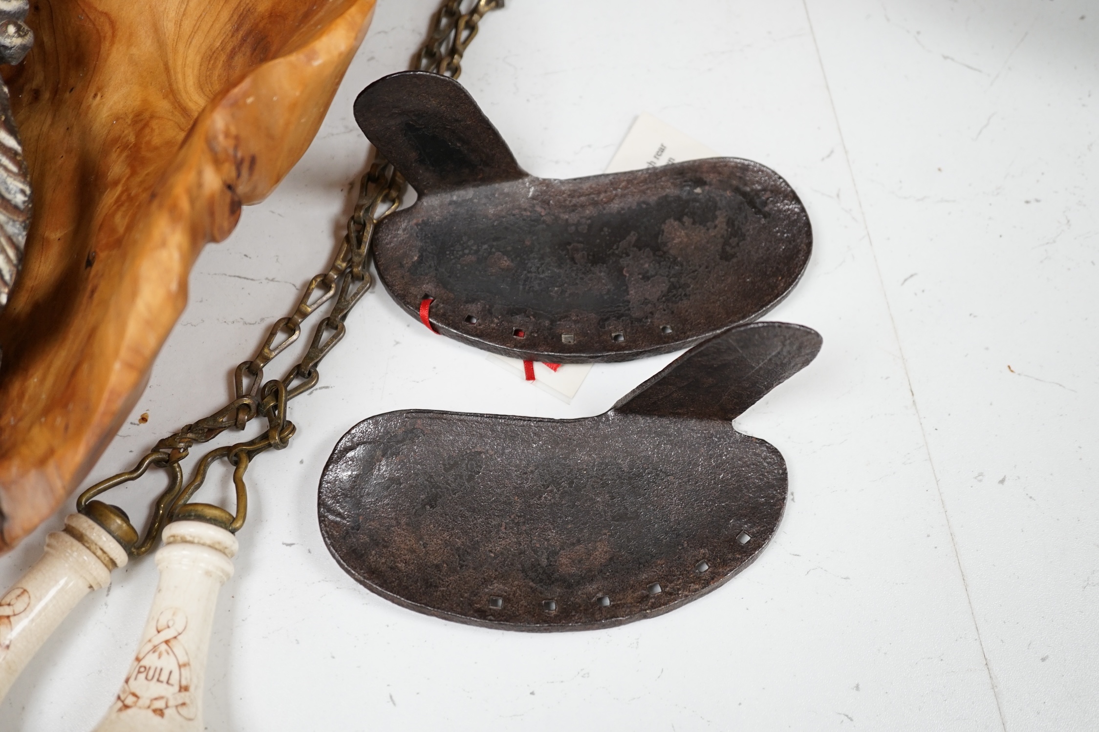 A cast iron toy model of a tricycle, a carved wooden bow, a classical figurative door knocker, a pair of metal cow shoes and two ceramic cistern pulls, bowl 30cm diameter. Condition - fair